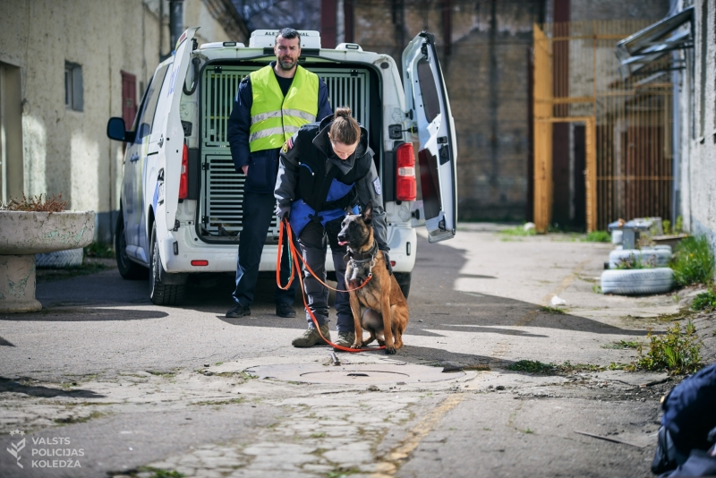 Valsts policijas darbinieki ar dienesta suni pie dienesta transportlīdzekļa