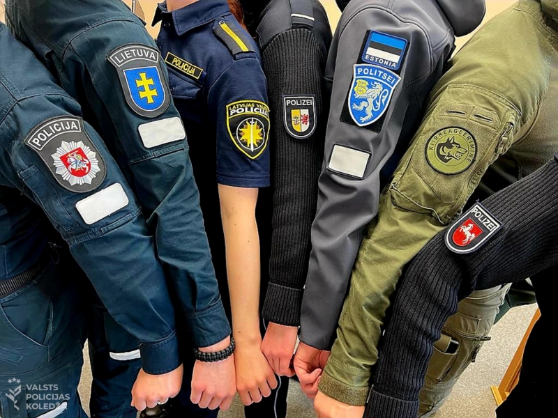 Latvijas, Lietuvas, Igaunijas un Vācijas policijas kadeti salikušu kopā rokas, lai redz emblēmas uz forma tērpiem
